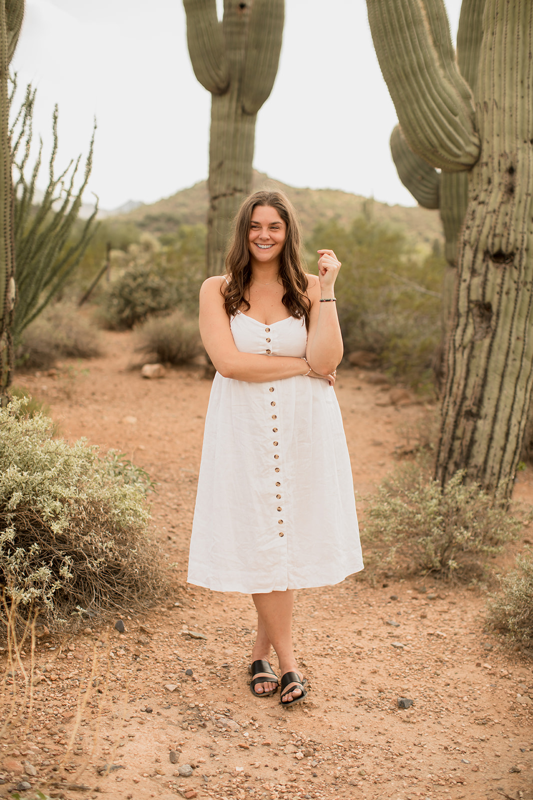 Heather Flynn in a white dress smiling among saguaro cacti in the desert